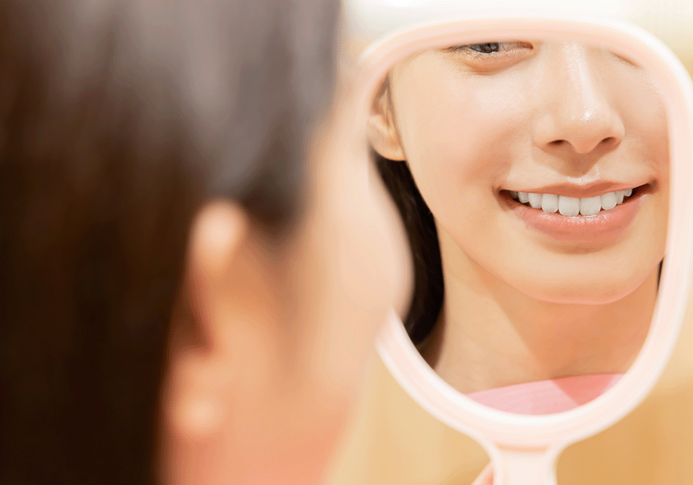 鏡で歯を確認する女性